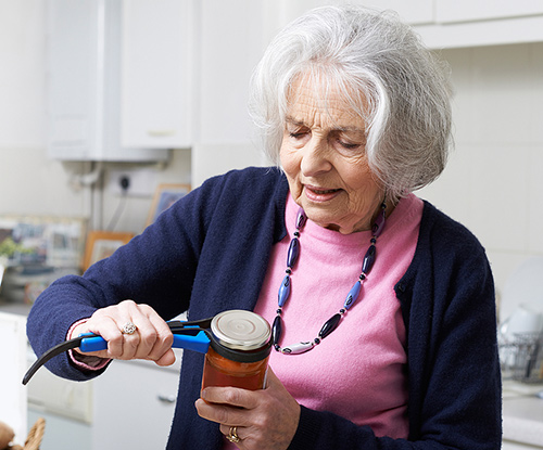 Woman using a gripper wrench assistive device to open a jar.