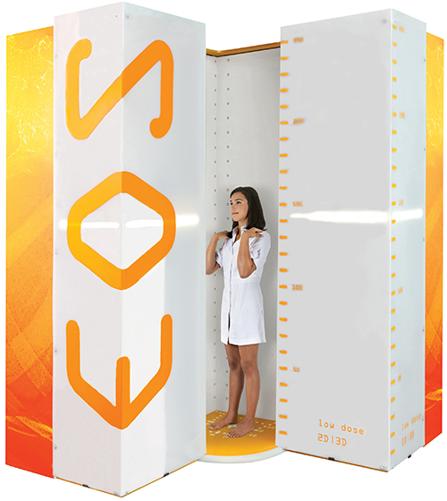 Photo of an EOS imaging cabin kiosk with an adolescent girl standing inside.