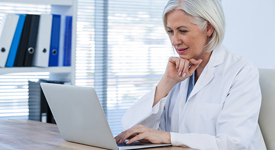 Female physician sitting at desk on her computer.