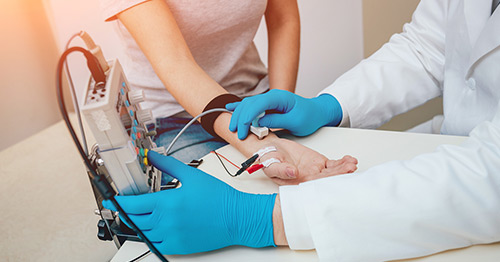 Image of a doctor doing an EMG trest on a patient's arm.