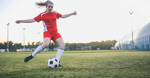 A female youth soccer player poised to strike.