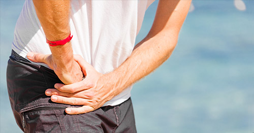 Younger or middle age male grasping hip in pain.