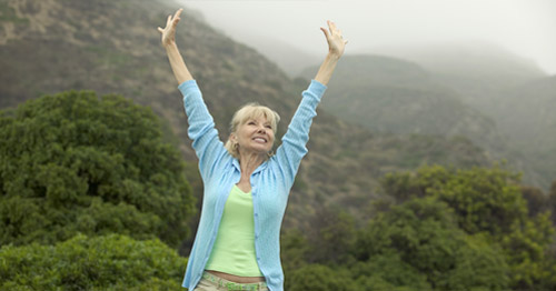 A woman with upstretched arms happy to be pain free.