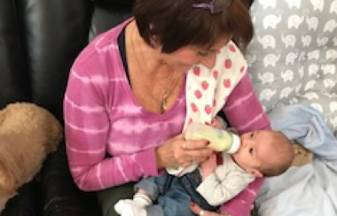 Senior woman feeding a baby his bottle