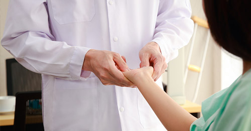 A doctor examining a woman's hand and wrist.