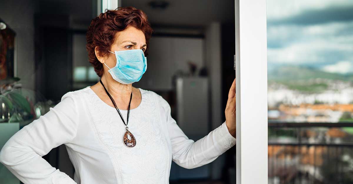 Woman with mask standing on balcony reflecting on life