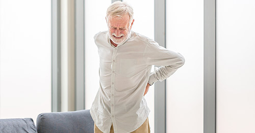 Older man holding lower back in pain.