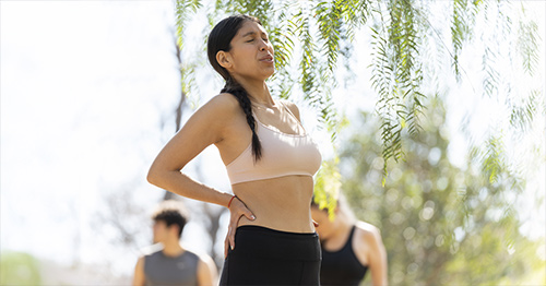 An athletic woman grimacing and holding her hip.