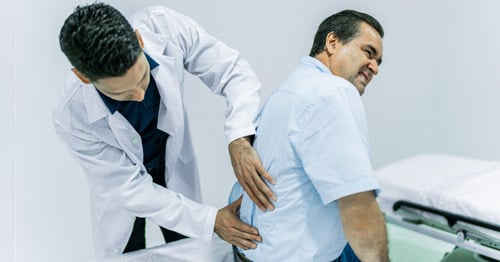 A doctor examining a man's back.