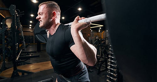 A male weightlifter grimacing.