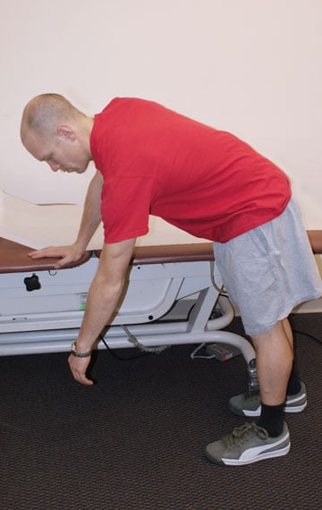 Man bending over with arm swaying in a pendulum motion.