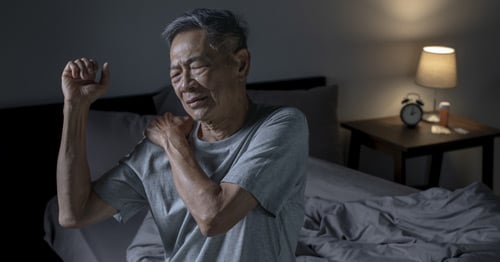 An older man holding his shoulder in pain.