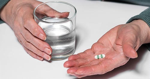 A hand holding a celecoxib capsule.