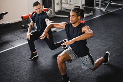 photo of a male exercise physiologist working with a young male athlete in a gym setting