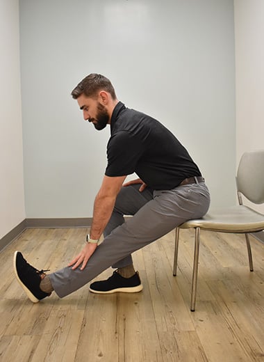man seated stretching his hamstrings