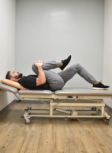 man in supine with knee bent to chest