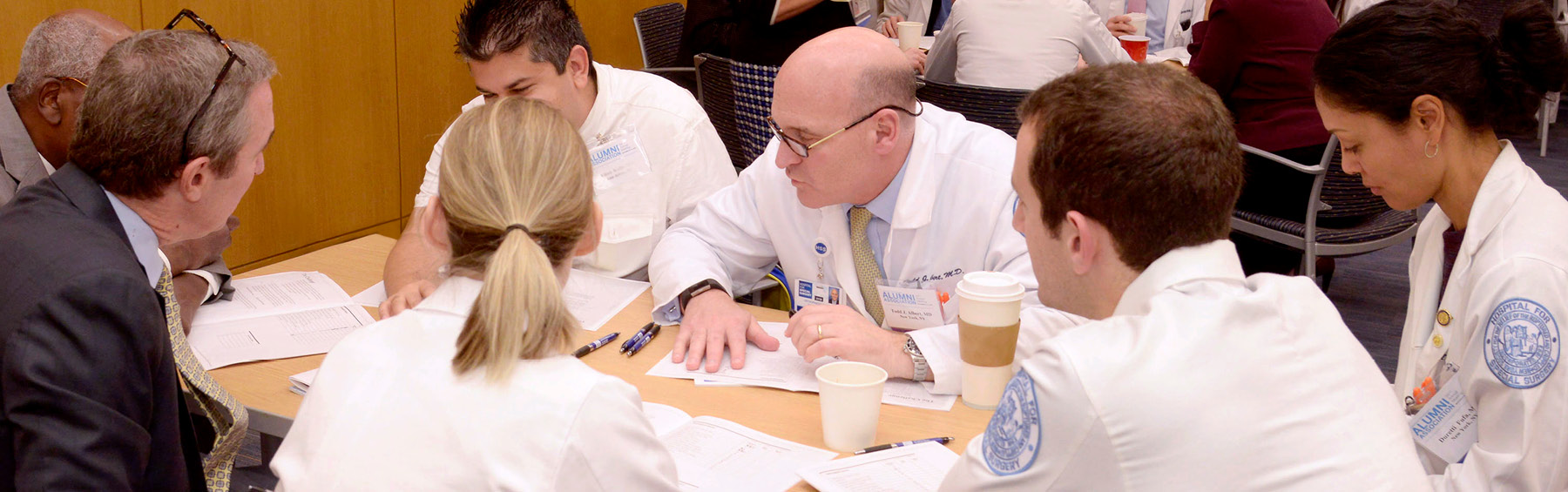 Banner image of Dr. Todd Albert having a round table discussion with physicians