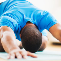 Athletic man doing child's pose on yoga mat