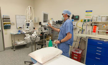 operating room with a male physician assistant setting up for the next surgery.