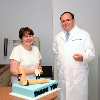 Photo of HSS patient Sarah Donnangelo presenting a cake to Dr. Hotchkiss