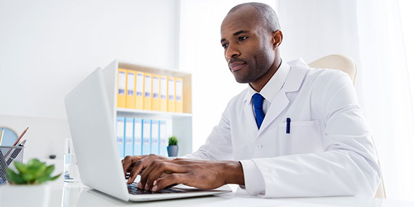 A male physician in his office on the computer
