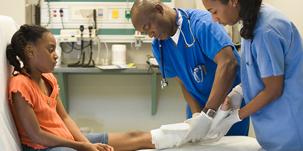 Two physicians treating a young female patient with a broken leg