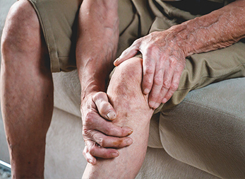 Older man grabbing knee in pain.