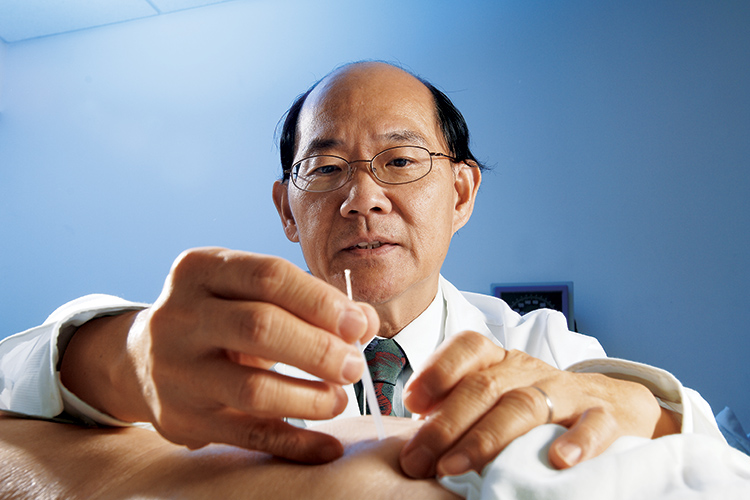 Photo of HSS anesthesiologist Jeffrey Y. F. Ngeow treating a patient using acupuncture.