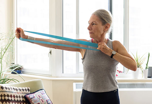  An older woman getting light exercise with fitness bands