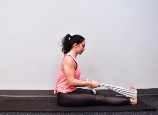 photo of cara demonstrating Seated hand-to-foot stretch