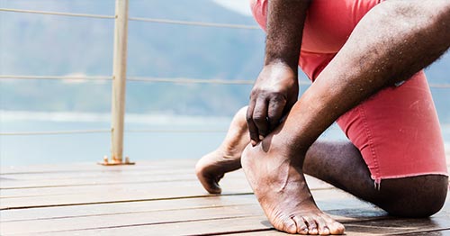 A man holding his Achilles tendon in pain.