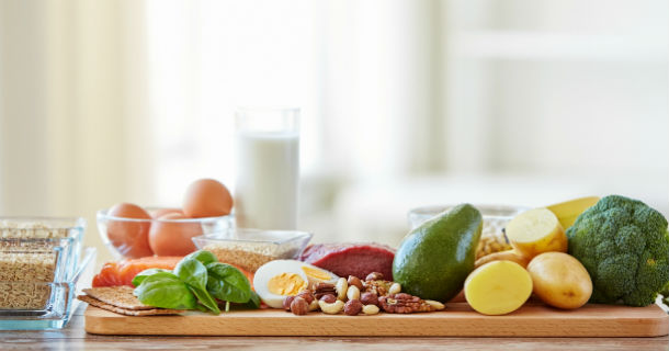 A table with fresh vegetables, eggs and milk.