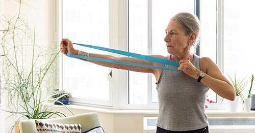 A woman using a stretch band to strengthen her elbow.