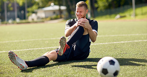 An athlete on a field with a knee injury.