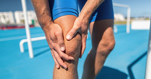 An athlete grasping the right knee in pain.