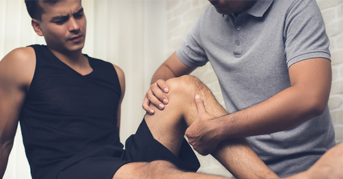 A physical therapist helping an athlete with knee tendonitis.