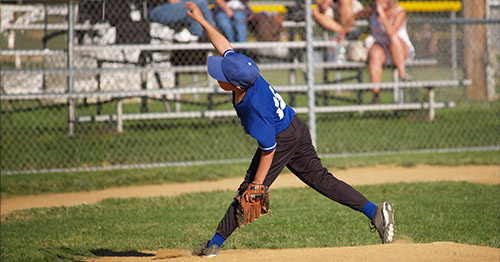 A little league baseball player pitching.