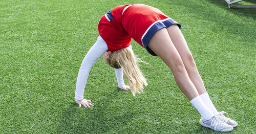 A cheerleader doing a back bend bridge.