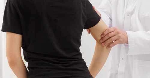 A doctor examining a patient's elbow.