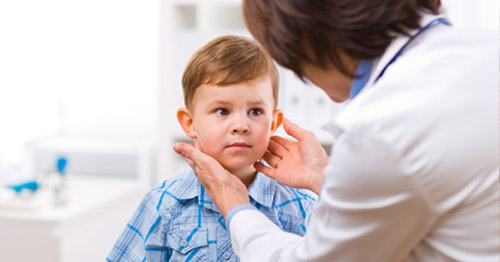 A doctor examining a child and palpating the neck.