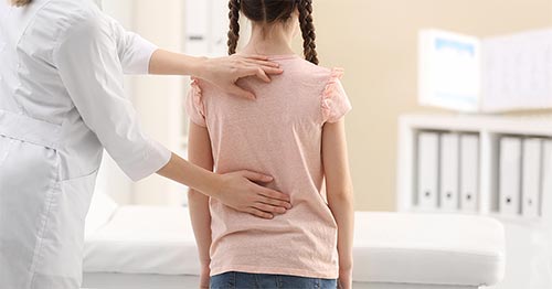 Doctor examining young girl's back.