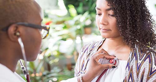 A doctor checking her patient's heartbeat.