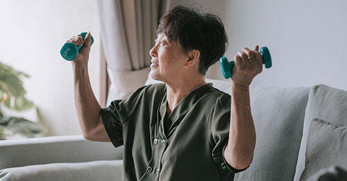 An older woman exercising with weights.
