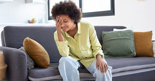 A woman feeling fatigued and holding her head.