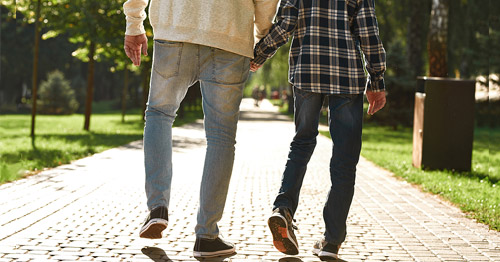 Boy with cerebral palsy walking with his father.