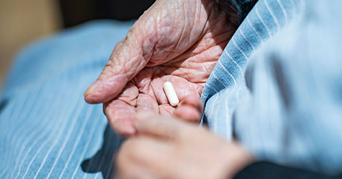 An older person holding medication.