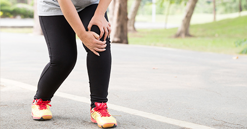 Woman grabbing her knee in pain.