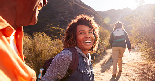 A woman and man smiling while hiking together.