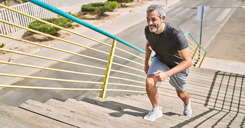 A middle-aged man in athletic wear running up a flight of stairs.