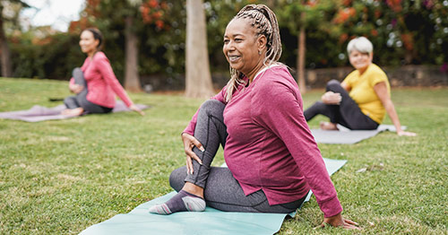 Middle-aged women doing yoga outside.